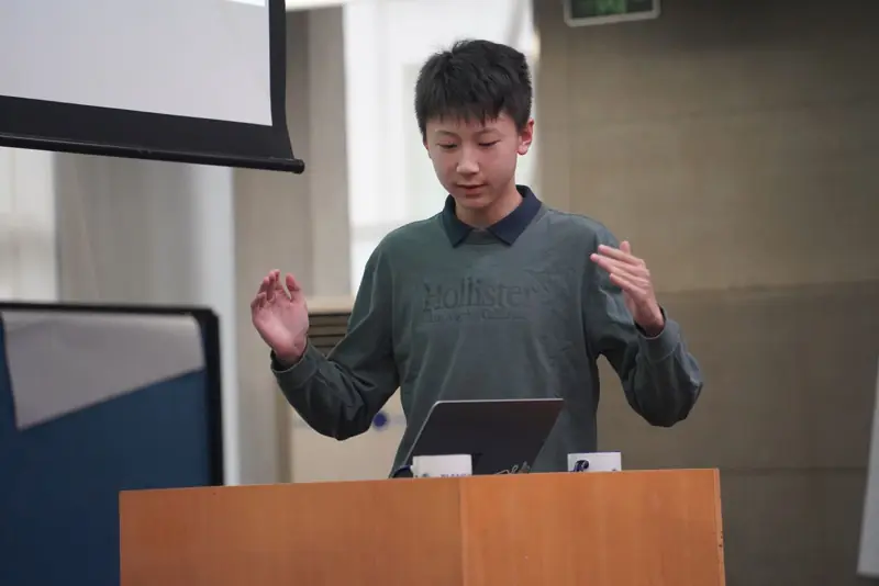 A presenter at a podium with slides behind